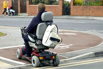 Mann im Rollstuhl fährt über Veloweg.