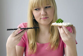 Bild eines Mädchens welches etwas ungesundes und etwas gesundes zu Essen in den Händen hält