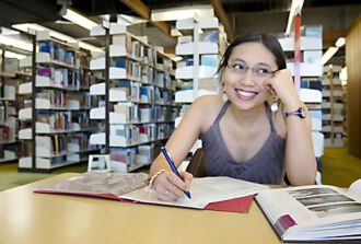Eine Jugendliche in der Bibliothek macht sich Notizen