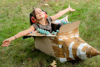 Spielendes Kind im selbst gebastelten Kartonflugzeug.