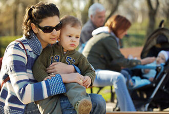 Mutter mit Kleinkind auf dem Schoss auf einer Parkbank.