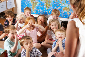 Kindergartenkinder zeigen auf Nachfrage ihrer Lehrerin auf ihre Nasen.