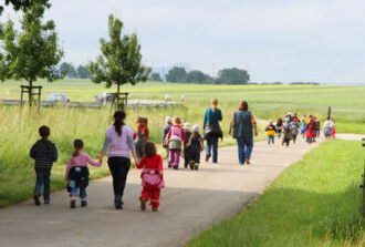 Eine Schulklasse wandern mit Lehrerinnen  über einen Spazierweg.