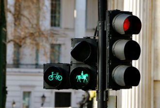 Bildausschnitt auf eine Ampel, die für den motorisierten Verkehr rot, für die Fahrradfahrer und Reiter grün anzeigt.