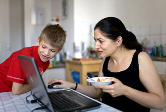 Mutter mit Kind am Essen und am Laptop