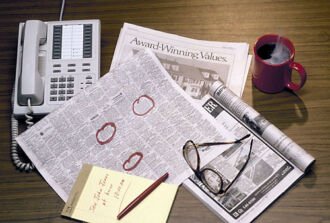Immobilienmarkt der Zeitung, ein Telefon, eine Brille, ein Tasse, Papier und Stift