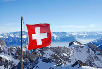 Bild einer Schweizerkreuz-Fahne und schneebedeckten Bergen